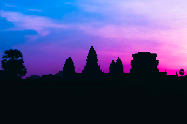Silhouette of Angkor Wat temple at sunrise with vibrant purple and blue sky in Siem Reap, Cambodia.
