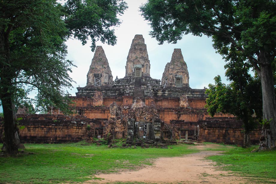 Front view of Pre Rup Temple’s main towers framed by tall trees on both sides under overcast weather.