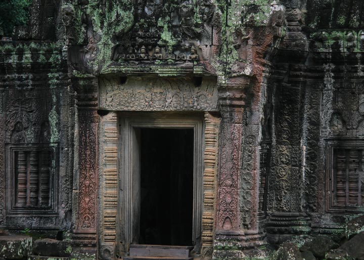 An intricately carved stone door frame at Ta Prohm Temple, showcasing classical Khmer architectural style.