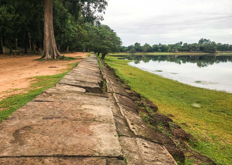 A photo of the Srah Srang reservoir in Cambodia, showing its stone terrace and the still water reflecting the morning light.
